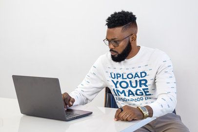 Crewneck Mockup of a Man Wearing Glasses Typing on a Computer in a Minimalist Workspace