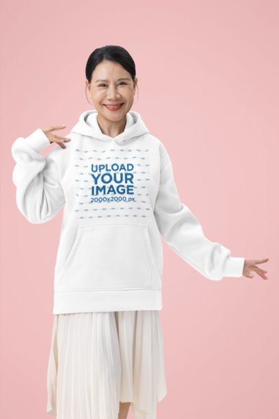 Pullover Hoodie Mockup of a Happy Older Woman Standing in a Studio Setting