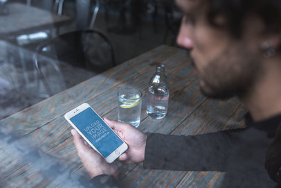 Through the Window iPhone Mockup Featuring a Man with Beard at a Restaurant