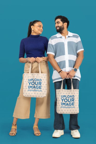 Tote Bag Mockup of a Happy Couple Holding Canvas Bags With a Customizable Background