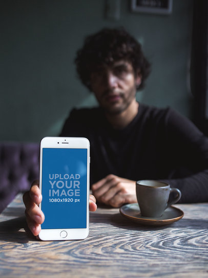 Mockup of a Man Holding an iPhone Against the Table