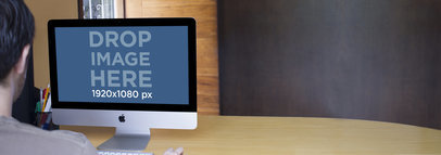 Mockup Template of a Young Man Working on an iMac