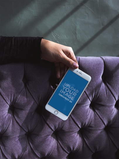 Mockup of a Silver iPhone 8 Plus Being Held Over a Pillow