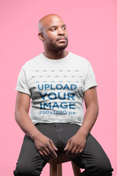 Mockup of a Serious Man Wearing a Tshirt Sitting on a Stool