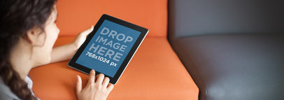 Tablet Mockup of a Young Woman on a Sofa Using an iPad