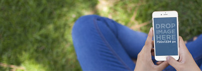 Mockup of an iPhone Stock Featuring a Woman Using Her iPhone Sitting on the Grass