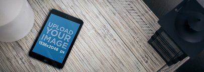 Tablet Mockup of a Black iPad Mini Over a Light Wooden Table
