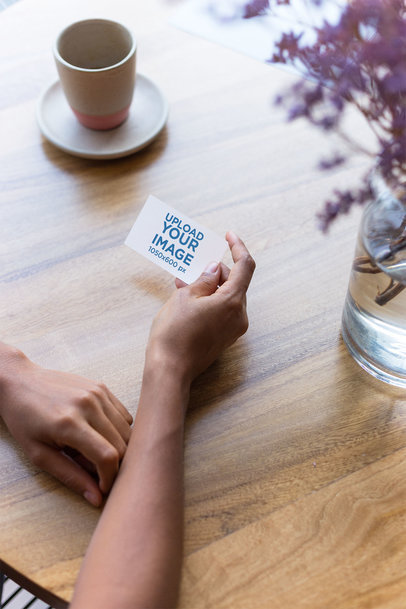 Mockup of a Business Card Being Held Next to a Coffee Cup