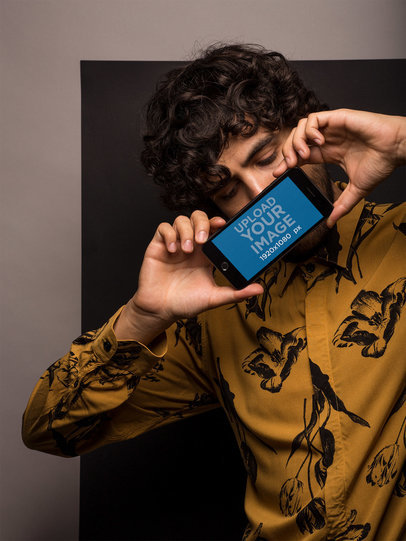 Mockup of a Young Man Holding an iPhone in Landscape Position