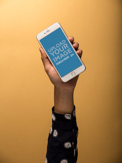 Mockup of an Arm Holding an iPhone Against a Yellow Wall 21776