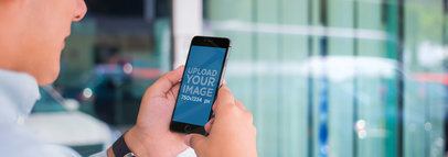 Mockup of a Young Man Standing in Front of a Window Using iPhone 6