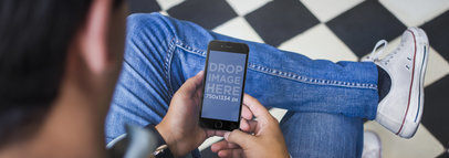 Mockup of a Young Man Holding a Black iPhone 6