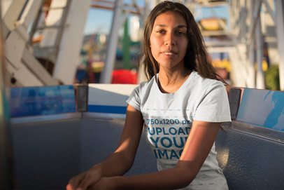 Mockup of a Woman Wearing a T-Shirt Sitting on a Ferris Wheel Cabin