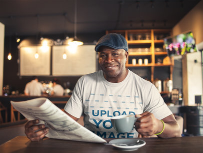 T-Shirt Mockup of a Man Having a Coffee while Reading the Newspaper