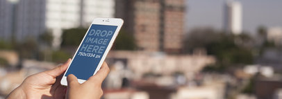 Mockup of a Woman Holding a White iPhone 6 at a Rooftop Terrace