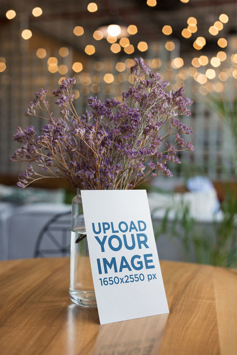 Flyer Mockup Leaning Against a Vase with Purple Flowers