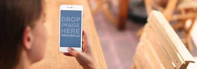 White iPhone 6 Mockup Featuring a Woman at a Cafe