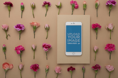 Silver iPhone Mockup on a Rectangular Cardboard Over a Surface with Flowers