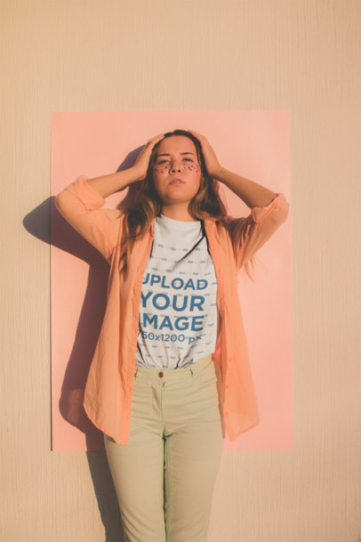 Crew-Neck Tee Mockup Featuring a Woman Wearing a Light Orange Shirt Posing Against a Salmon Color Cardboard