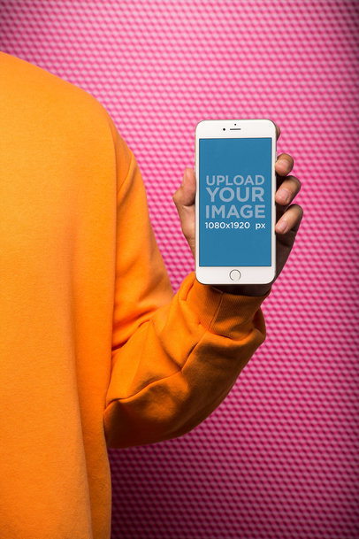 Arm Holding a Silver iPhone Mockup In Front of a Textured Background