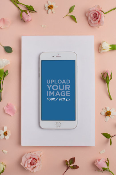 iPhone on a White Cardboard Mockup Featuring Flowers on a Soft Pink Surface
