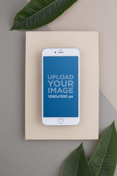 Mockup of Silver iPhone 8 Plus over a Varied Neutral Colored Background with Leaves Surrounding it 21837