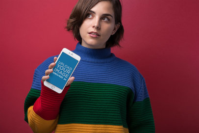iPhone 8 Mockup Featuring a Short-Haired Girl in a Mock-Neck Sweater Against a Red Wall 21830