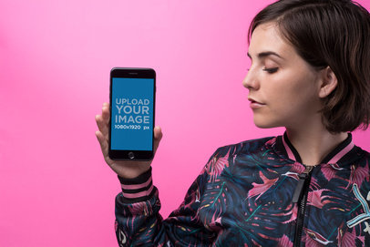Space Gray iPhone Mockup of a Young Woman Wearing a Bomber Jacket Against a Pink Wall 21847