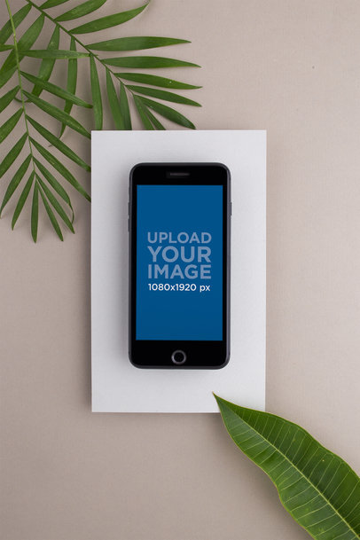 Space Gray iPhone Mockup on a White Rectangular Paper Surrounded by Green Leaves 21824