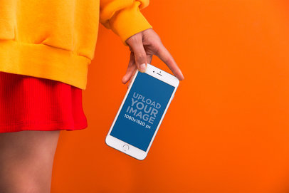 Mockup of the Hand of a Woman Showing a Silver iPhone 8 Against a Vivid Orange Background  21970