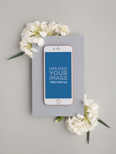 iPhone Mockup on a Gray Cardboard Rectangle Over White Flowers