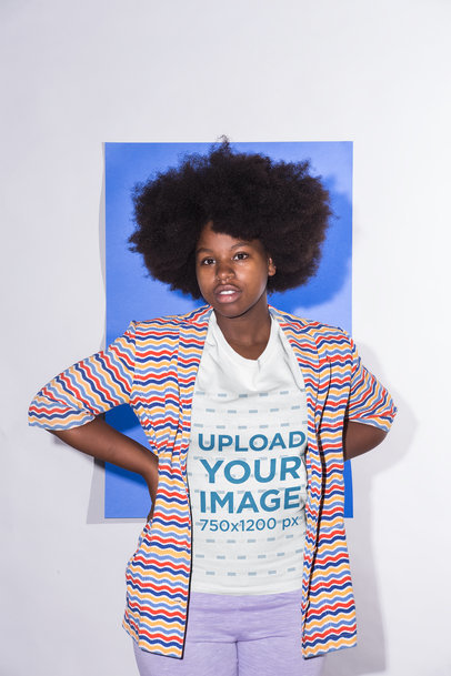 Crew Neck Tee Mockup Featuring a Girl with an Afro Hairstyle and a Multicolored Striped Jacket Against a Sapphire Blue Cardboard 21713