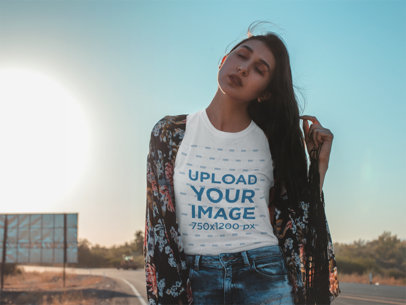 Tshirt Mockup Featuring a Woman with an Indie Outfit Posing by a Desert Road