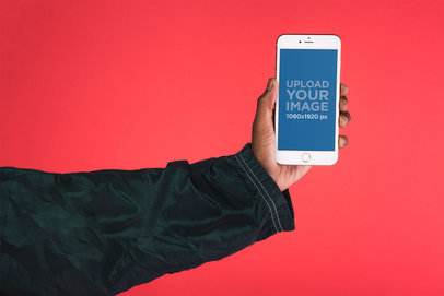 Mockup Featuring a Male Hand Holding an iPhone 8 Against a Bright Red Background 22127