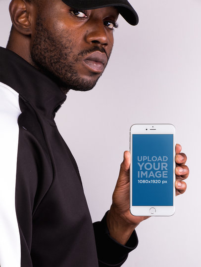 Mockup of a Man in a Street Style Outfit Holding an iPhone 8 Plus