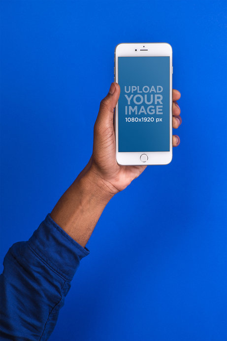 Mockup Featuring the Hand of a Man Holding a Silver iPhone 8 Against a Cobalt Blue Background  
