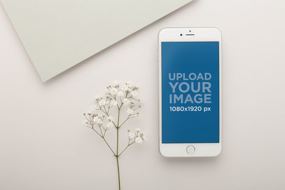 Silver iPhone Mockup Lying Next to Small White Flowers
