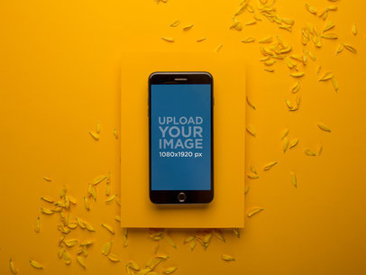 Space Gray iPhone Mockup Placed on an Amber Surface with Small Petals 