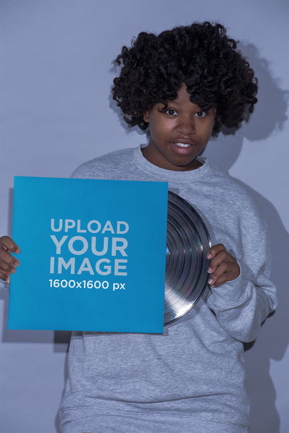 Mockup of a Girl Wearing a Gray Sweatshirt Holding a Vinyl Album Cover 22115
