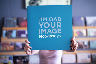 Mockup of a Woman Holding a Vinyl Cover in Front of Her Face with a Blurry Background 