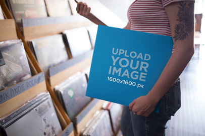Mockup Featuring a Woman Holding a Vinyl Album Cover at a Vinyl Record Shop