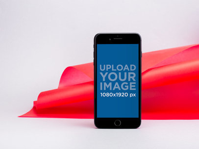 iPhone 8 Mockup Standing Against a Bent Red Paper