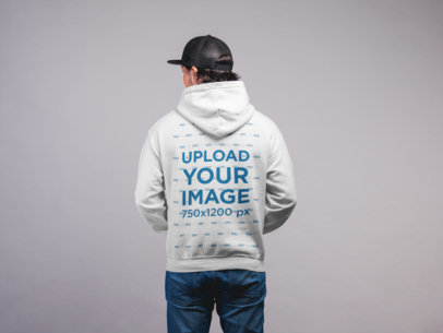 Hoodie Mockup Featuring a Man with a Cap Against a Flat Wall