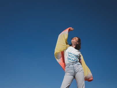T-Shirt Mockup of a Woman Standing In Front of a Clear Blue Sky