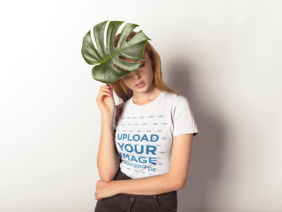 T-Shirt Mockup of a Woman Holding a Large Leaf to Her Head