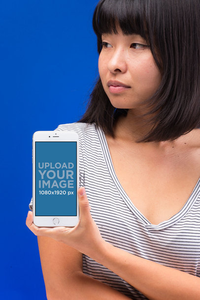 Mockup of a Serious Woman with an iPhone 8 Against a Bright Blue Background