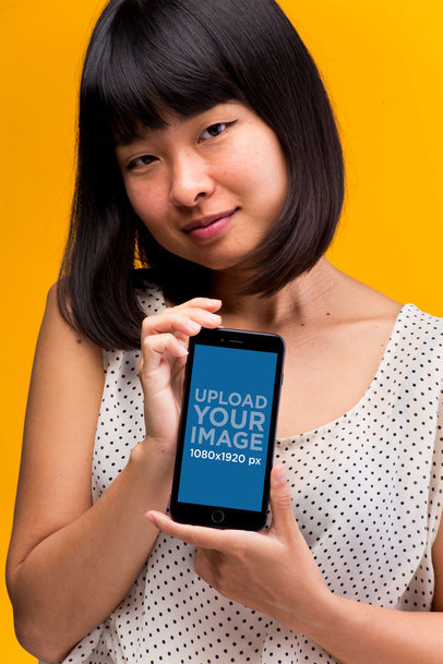 Mockup of an iPhone 8 Plus Held by a Woman Wearing a Polka Dot Shirt
