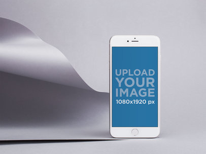 Silver iPhone 8 Mockup Standing by a Silver Pasteboard in a Gray Room