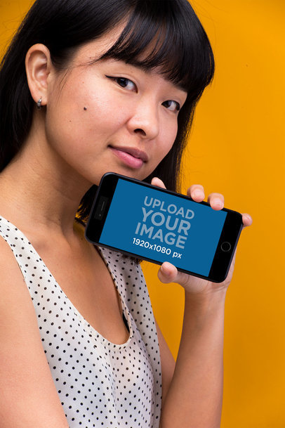 iPhone 8 Plus Mockup Held by a Woman In Front of an Orange Backdrop