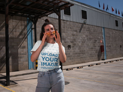T-Shirt Mockup of a Woman Standing in Front of a Warehouse